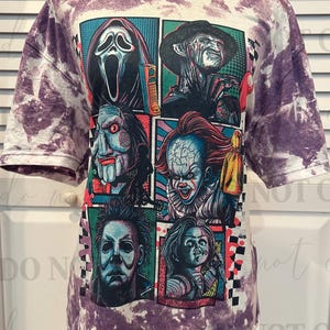 K&ouml;nnte beinhalten: Kurz&auml;rmeliges T-Shirt mit lila Batikmuster. Auf der Vorderseite befindet sich eine Grafik von Horrorfilmfiguren im Comic-Stil, darunter Ghostface, Freddy Krueger und Pennywise.