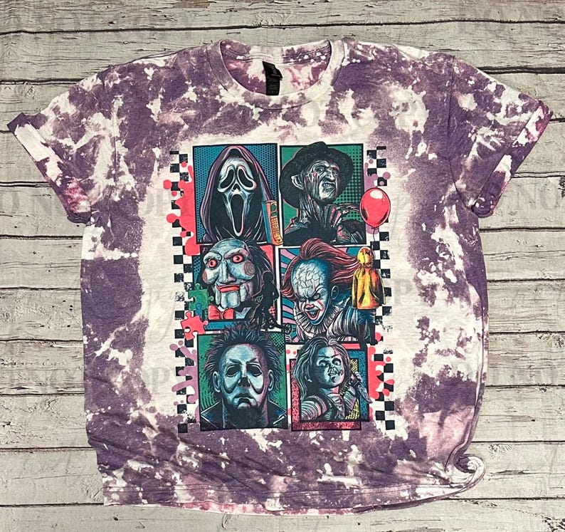 K&ouml;nnte beinhalten: Lila und wei&szlig;es Batik-T-Shirt mit einer Grafik von Horrorfilmfiguren. Die Grafik zeigt Scream, Freddy Krueger, Jigsaw, Pennywise, Michael Myers und Chucky. Das Shirt hat einen Rundhalsausschnitt und umgeschlagene &Auml;rmel.