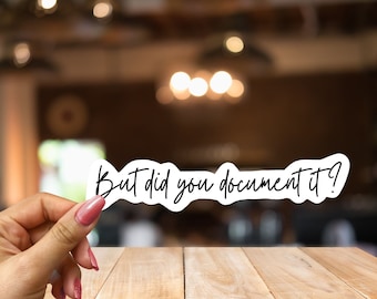 May include: White sticker with black text that reads "But did you document it?"  The sticker is being held by a hand with pink nail polish.