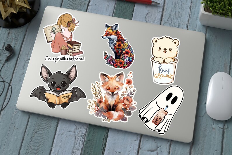 May include: A collection of colorful stickers featuring whimsical illustrations. Designs include a girl reading with the text "Just a girl with a bookish soul", a fox with floral details, a bear in a cup with "Keep Growing", a bat reading, a fox with flowers, and a ghost with boba.