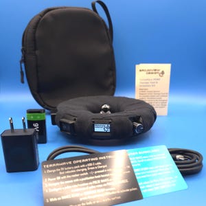 May include: A black fabric-covered ring-shaped therapy device with a Broadview Design logo, a rocker switch, and a control knob. Includes a black carrying case, a 9V battery, a power adapter, a USB-C cable, and printed operating instructions.