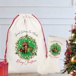 Peut inclure: Un sac cadeau et une chaussette de Noël crème avec un cordon de serrage et une bordure rouges. Le sac et la chaussette présentent un dessin de raton laveur et de Groot de dessin animé à l'intérieur d'une couronne avec le texte "Special Delivery For Amelia" et "Merry Christmas."