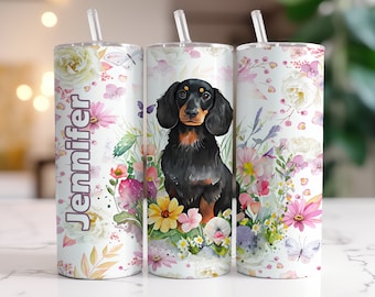 May include: Three stainless steel tumblers with a floral design and a dachshund dog illustration. The tumbler on the left has the name "Jennifer" printed on it.