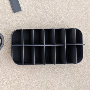 Op de afbeelding: Een zwarte Pelican 1040 Go Case met een uitneembaar dienblad. De koffer heeft een sluiting en een handvat. Het dienblad heeft 12 vakken.