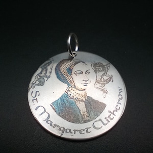 May include: Silver pendant with a round, engraved image of St. Margaret Clitherow. The image is in shades of brown, blue, and white. The pendant has a silver loop for attaching a chain.