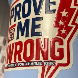 Puede incluir: Un recipiente azul claro con una pegatina que dice "PROVE ME WRONG" en letras rojas y azul marino. La pegatina también incluye el texto "2025" y "#JUSTICE FOR CHARLIE KIRK". Un rayo rojo con tres estrellas también es visible.