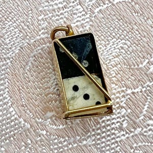 Peut inclure: Un pendentif doré en forme de domino noir et blanc avec un cadre doré. Le domino a des points noirs d'un côté et des points blancs de l'autre.