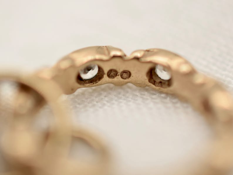 May include: Close-up of the underside of a gold ring with two small clear stones set into the band.