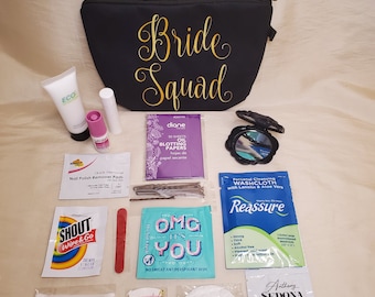 May include: A black zippered cosmetic bag with the words "Bride Squad" in gold script, surrounded by various beauty and personal care items. Includes blotting papers, makeup remover wipes, bandages, and a compact mirror.