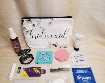 May include: A white canvas zippered pouch with a floral print and the word "bridesmaid" printed in black. The pouch is filled with various items, including a small bottle of hand sanitizer, a compact mirror, a pink makeup sponge, a small tube of lotion, a small packet of cleansing wipes, a small packet of hair ties, a small packet of cotton rounds, a small packet of bandaids, a small packet of washcloths, and a small packet of facial wipes.