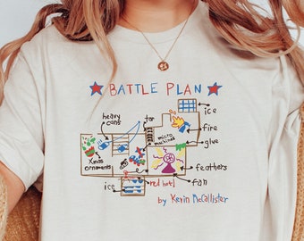 May include: White t-shirt with a hand-drawn illustration of a house floor plan with the text "BATTLE PLAN" and "by Kevin McCallister".