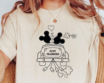 May include: A white t-shirt featuring a black graphic of Mickey and Minnie Mouse in a car with the text "Just Married".