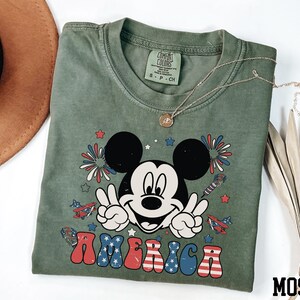 a mickey mouse t - shirt with a straw hat next to it