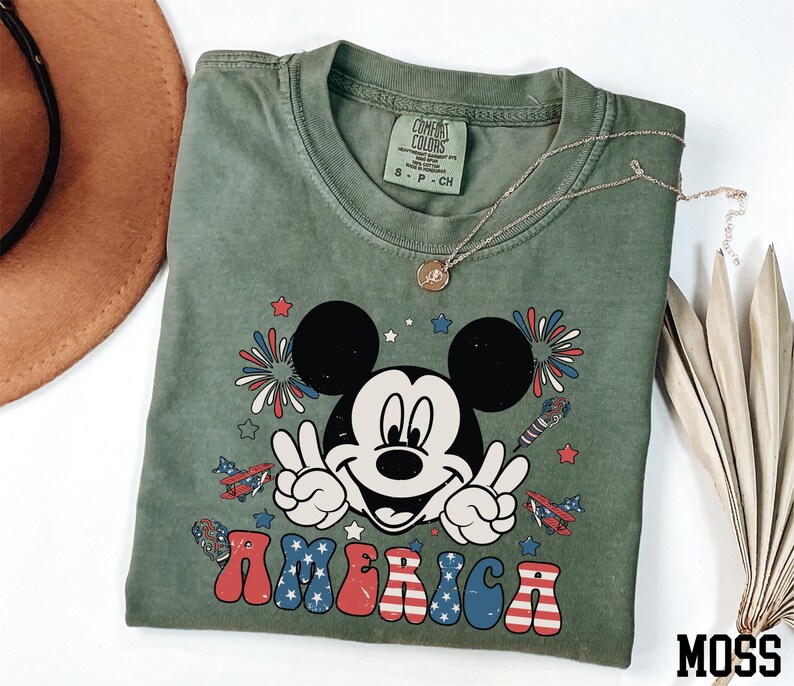 a mickey mouse t - shirt with a straw hat next to it