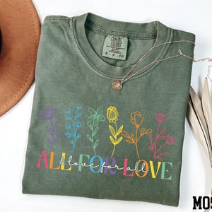 May include: Green t-shirt with a rainbow floral design and the text "All & love for all LOVE".