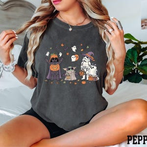 A woman wearing a black t-shirt with a Halloween-themed graphic design featuring characters from the Star Wars franchise.