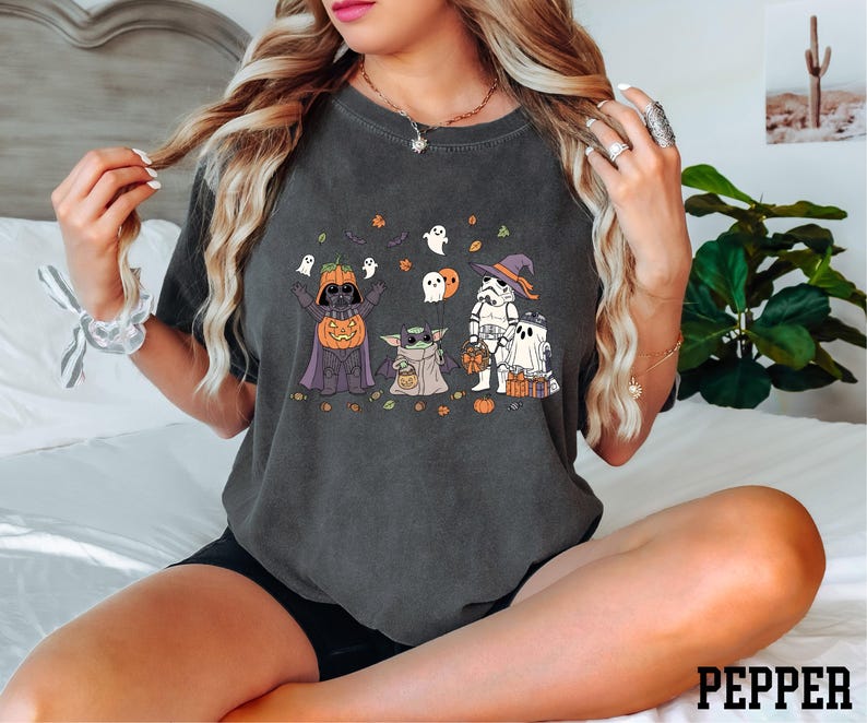 A woman wearing a black t-shirt with a Halloween-themed graphic design featuring characters from the Star Wars franchise.