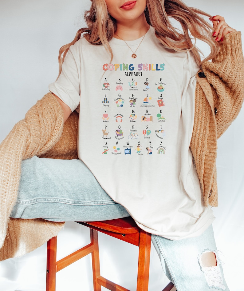 May include: White t-shirt with a colorful alphabet chart that lists coping skills for each letter. The chart is titled "Coping Skills Alphabet".