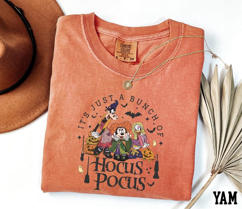 A red t-shirt with a Halloween-themed graphic design, including characters from the Disney movie Hocus Pocus, along with the text "It's just a bunch of Hocus Pocus".