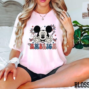 a woman sitting on a bed wearing a minnie mouse shirt
