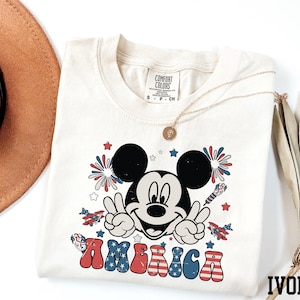 a mickey mouse t - shirt with a straw hat next to it