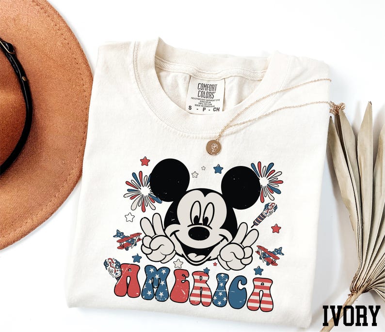 a mickey mouse t - shirt with a straw hat next to it
