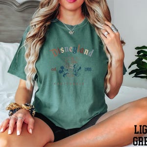 a woman sitting on top of a bed wearing a green shirt