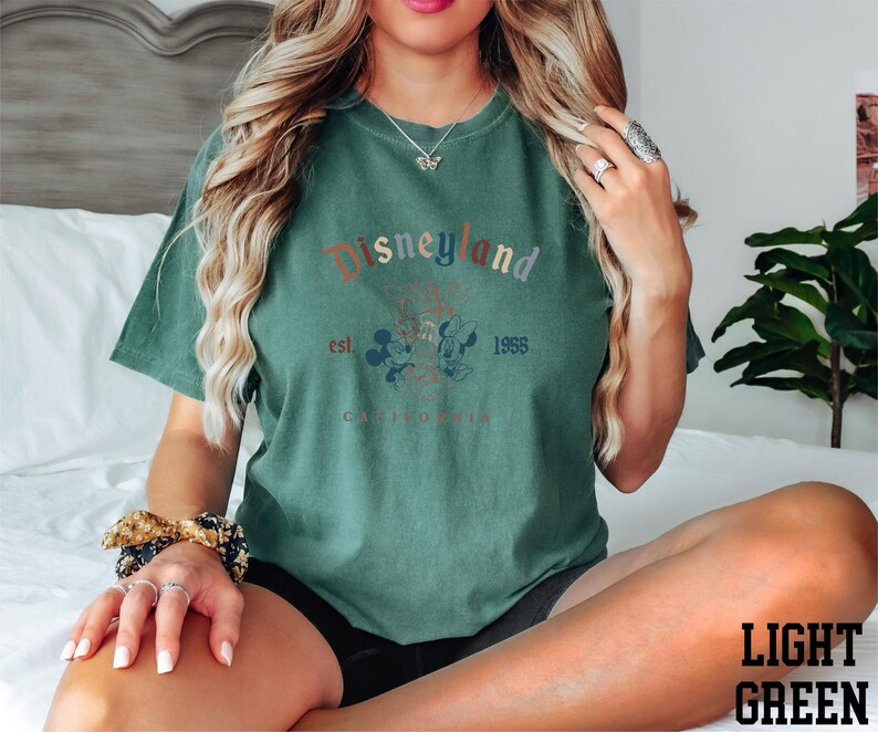 a woman sitting on top of a bed wearing a green shirt
