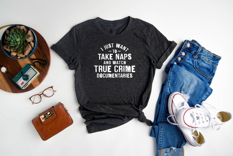 May include: A dark gray t-shirt with the text "I just want to take naps and watch true crime documentaries" printed in white.
