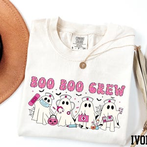 A white t-shirt with a graphic design featuring a group of ghost characters, including a nurse, on a white background.
