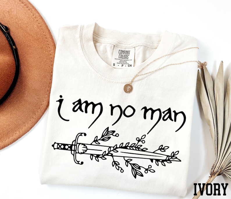 a t - shirt that says i am no man next to a hat