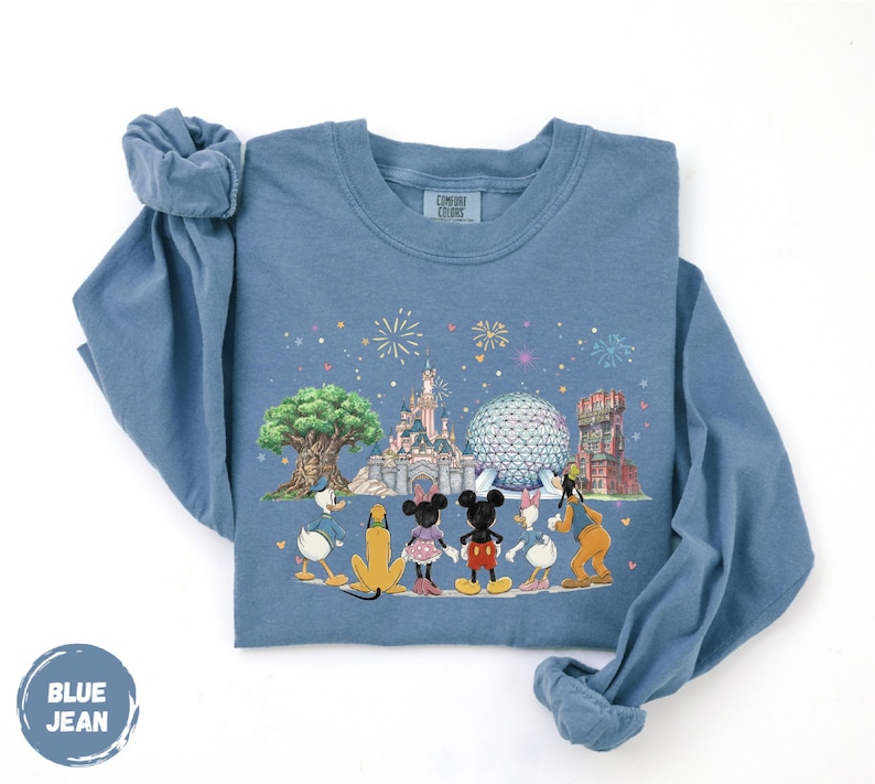 A blue long-sleeved t-shirt with a graphic design depicting Disney characters and landmarks, including Mickey Mouse, Goofy, Donald Duck, and the Eiffel Tower.