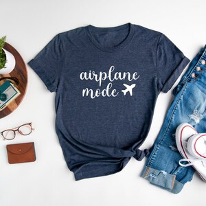 Puede incluir: Una camiseta azul marino con el texto "airplane mode" y un avi&oacute;n blanco.