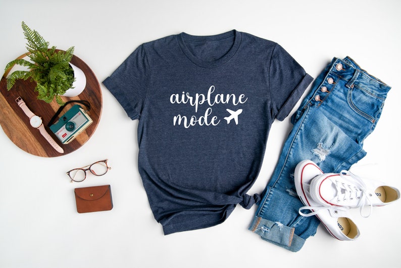 Puede incluir: Una camiseta azul marino con el texto "airplane mode" y un avi&oacute;n blanco.