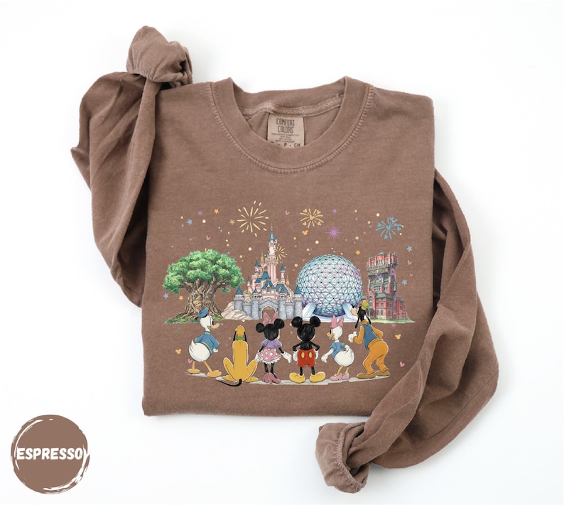 A brown t-shirt with a printed design depicting Disney characters and landmarks, including Mickey Mouse, Donald Duck, Goofy, and Eiffel Tower.