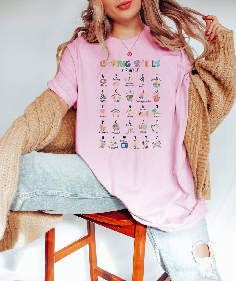 May include: Pink t-shirt with the text "Coping Skills Alphabet" and a colorful alphabet chart with coping skills for each letter.