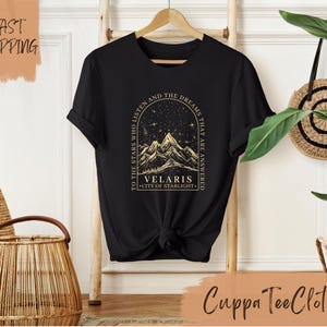 a black t - shirt with a picture of a mountain and stars on it