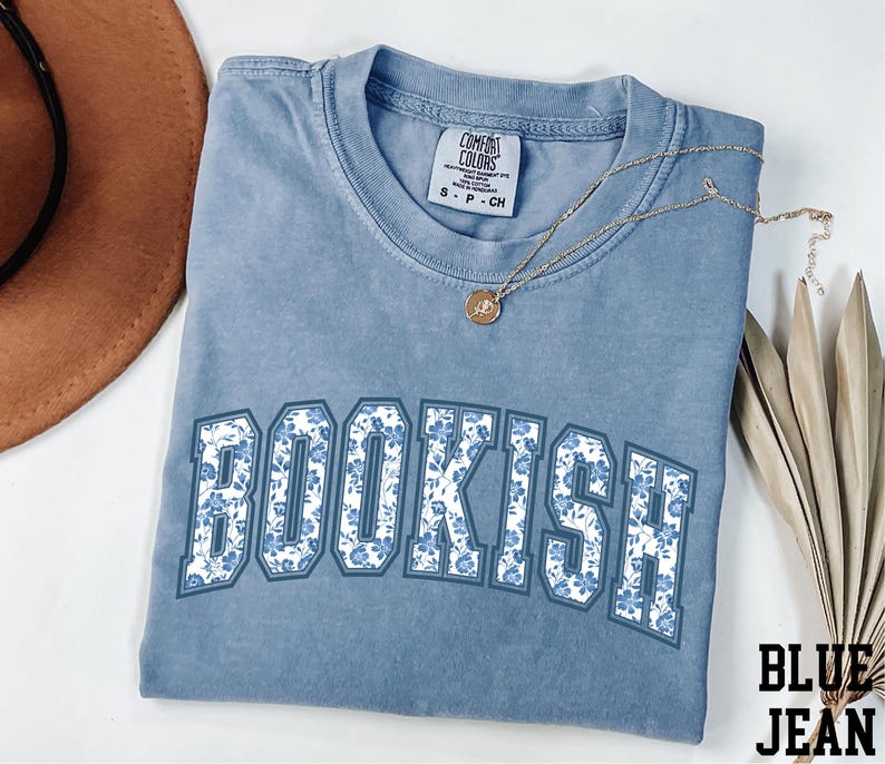 a blue t-shirt with the word "BOOKISH" printed on it, along with a brown hat and some leaves.