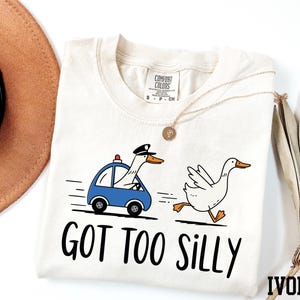 a t - shirt with a duck driving a car and a hat next to it