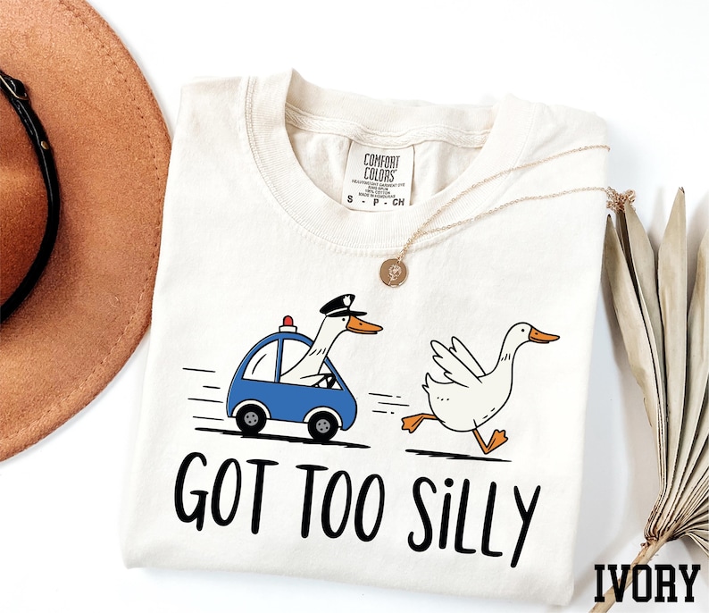 a t - shirt with a duck driving a car and a hat next to it