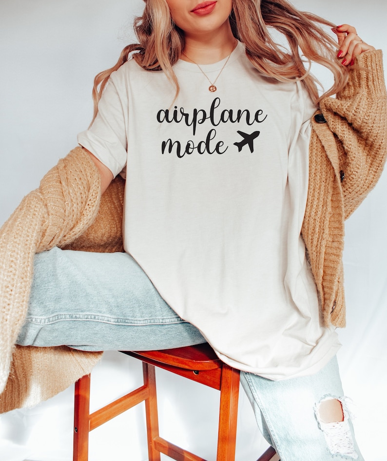 Puede incluir: Una camiseta blanca con el texto "airplane mode" y un peque&ntilde;o icono de avi&oacute;n impreso en negro.