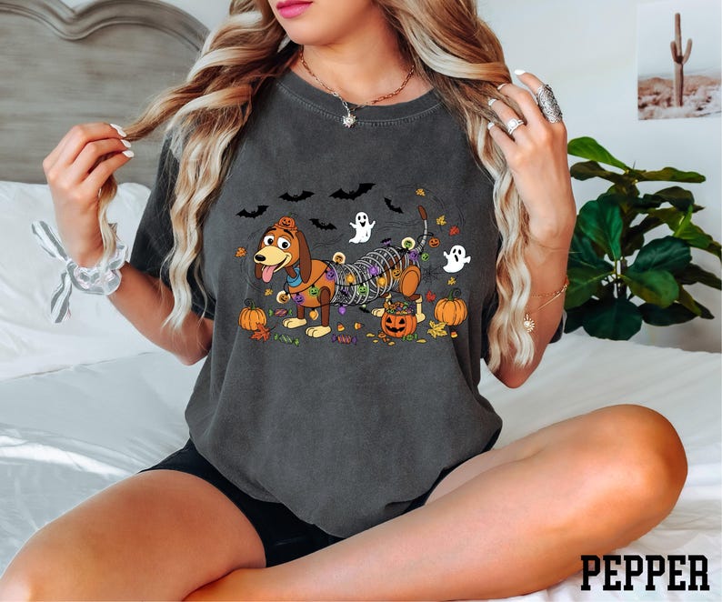 A woman wearing a t-shirt with a Halloween-themed graphic of a dog and various spooky elements.