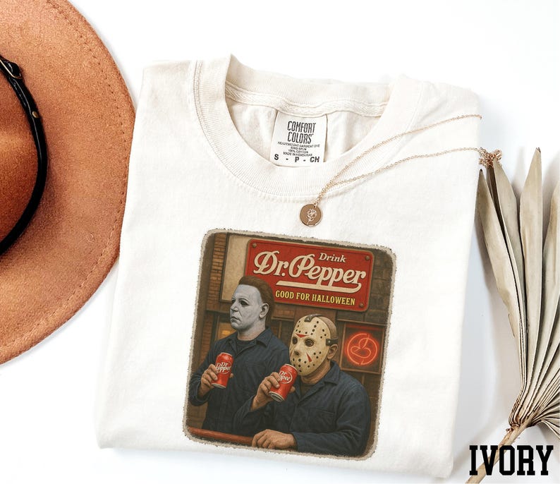 a white t-shirt with a graphic design depicting two men wearing masks, one holding a can of Dr. Pepper.
