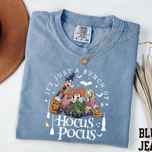 A blue t-shirt with a Halloween-themed graphic design, including characters from the Disney movie "Hocus Pocus".