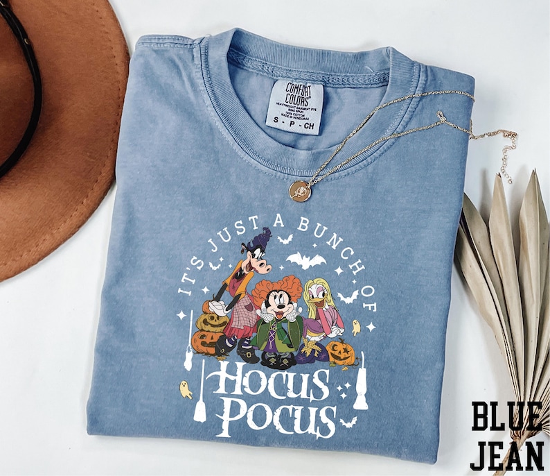 A blue t-shirt with a Halloween-themed graphic design, including characters from the Disney movie "Hocus Pocus".