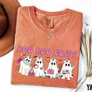 a t-shirt with a Halloween-themed design, including a group of ghost characters and a nurse character, along with the text "BOO BOO CREW".