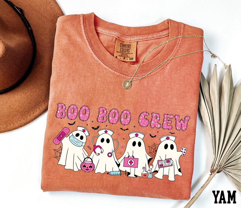 a t-shirt with a Halloween-themed design, including a group of ghost characters and a nurse character, along with the text "BOO BOO CREW".