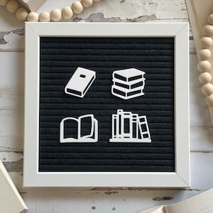 May include: A black felt letter board with white felt letters spelling out different book-related icons. The icons include a single book, a stack of three books, an open book, and a bookshelf with five books.