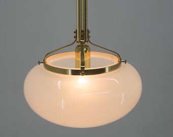 May include: A brass pendant light fixture with a white frosted glass shade. The light is hanging from a chain.