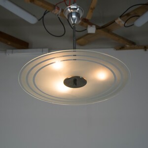 May include: A frosted glass ceiling light fixture with three light bulbs and a silver metal base.